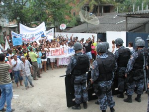 Riot police watch as residents display signs and banners