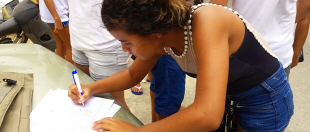 Ananda Trajano, a 15-year-old student and member of Coletivo Papo Reto, signs the petition for the implementation of an IFRJ in Complexo do Alemão.
