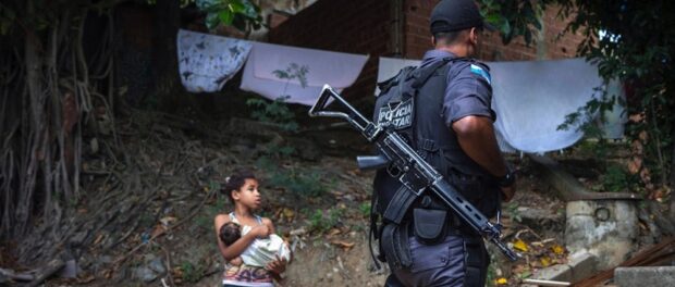 Police officer passes a young resident of Lins following the occupation of the community. Photo by Luiz Baltar / Imagens do Povo