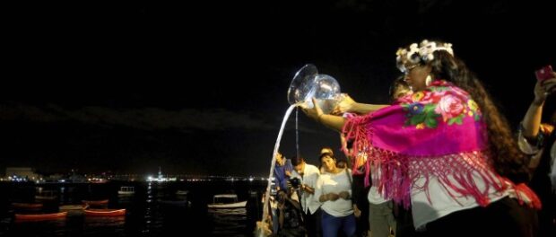 Attendees watch as the water they brought with them from home is poured into the Guanabara Bay. Photo from O Globo