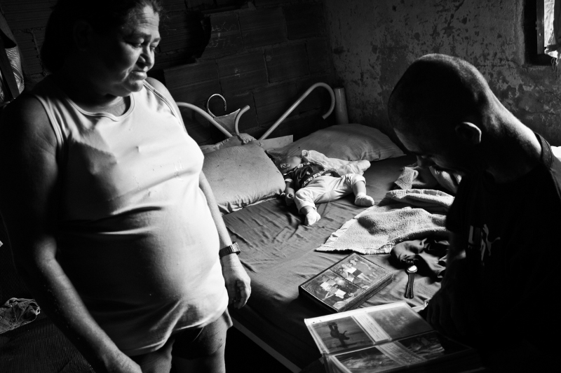 Dona Maria Evanilde and Senhor Carlos in their bedroom looking at family photos. 