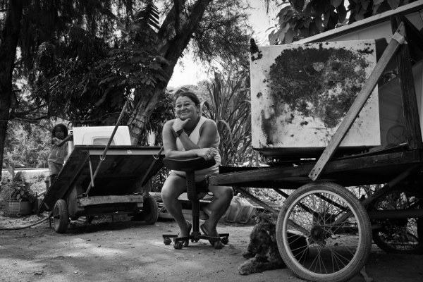 Dona Maria Evanilde sat among the scrap metal she works with, in front of her house.