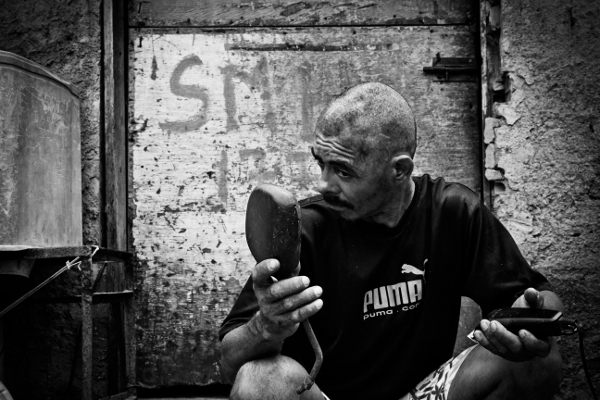 Senhor Carlos cuts his hair in front of his home.