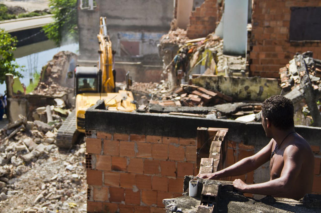 A resident looks on as a neighbor's home is demolished. Photo by AF Rodrigues