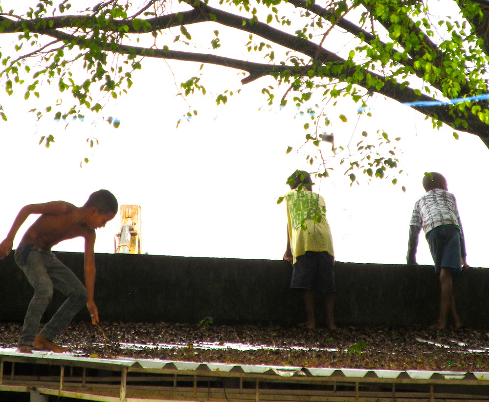 Vila Autodromo kids playing viewing Olympic works over roof 03