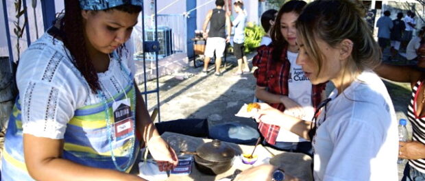 A VilAtiva member dressed in traditional Baiana clothing handed out free samples of northeastern Brazilian cuisine