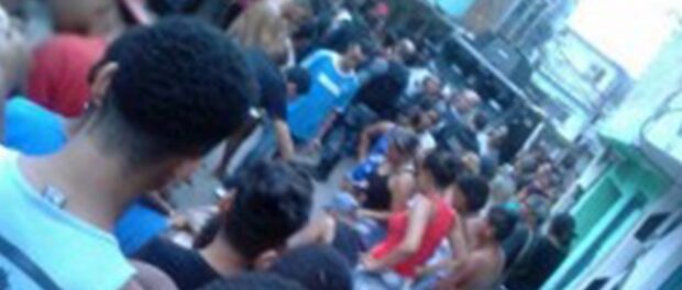 Bystanders look over Rodrigo's body in the street. Photo: Alemão Notícias