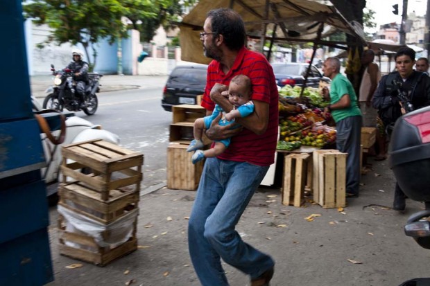 “Father runs to protect his baby” from the album “Violence in Complexo do Alemão,” taken during the police occupation of the favela. Photo by AF Rodrigues, September 26, 2010