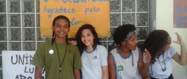 Students pose in front of signs at Mendes de Moraes