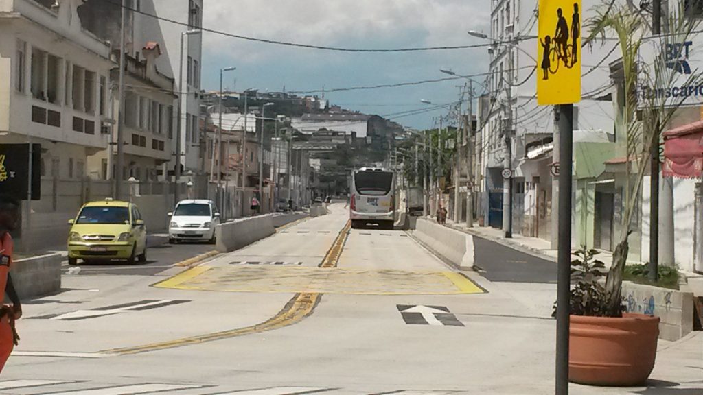 Residential streets, previously lined with trees, turned into hot ovens irradiating heat from the non-sidewalked street. In the upper-right corner, a sign indicates a speed-limit of 20 km/h, due to the possibility of children on the BRT thoroughfare.