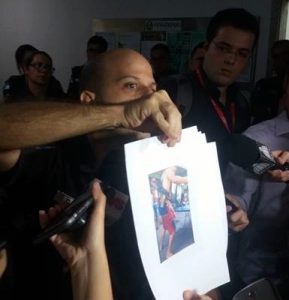 Captain Zuma, UPP captain for Nova Brasília, shows photos of armed traffickers.