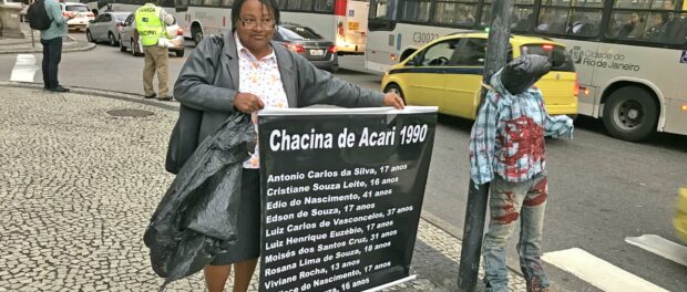 Ana Lúcia, of the Network Against Violence, holds sign honoring those dead in the Acari massacre of 1990