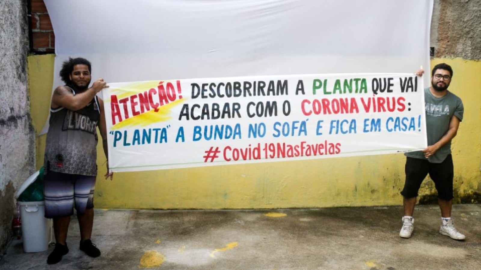 INTEGRANTES DO COLETIVO PAPO RETO SEGURANDO UMA DAS FAIXAS QUE ESTÃO COLOCANDO NAS FAVELAS. FOTO: BENTO FABIO/ COLETIVO PAPO RETO