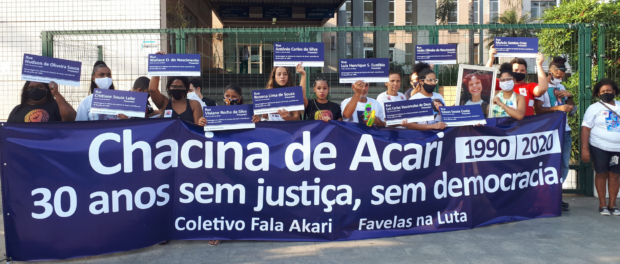 Mothers, fathers and relatives of victims of the state and favela activists hold a banner that reads ‘Acari Massacre, 30 years without justice, without democracy’ and street signs with the names of the 11 abducted youth in the massacre.