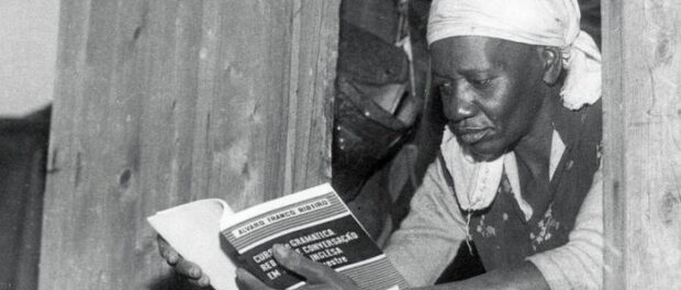 Carolina Maria de Jesus by the window in her house, probably in favela do Canindé, in São Paulo, reading an English course book. Photo: UH/Folhapress.